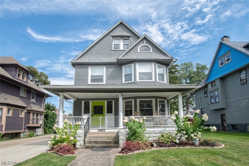 Victorian-style house featuring covered porch and a garden with hydrangeas.