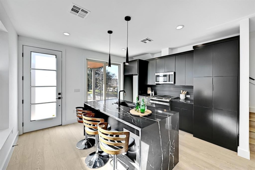 Kitchen with stainless steel appliances, dark cabinets, light wood-type flooring, and recessed lighting