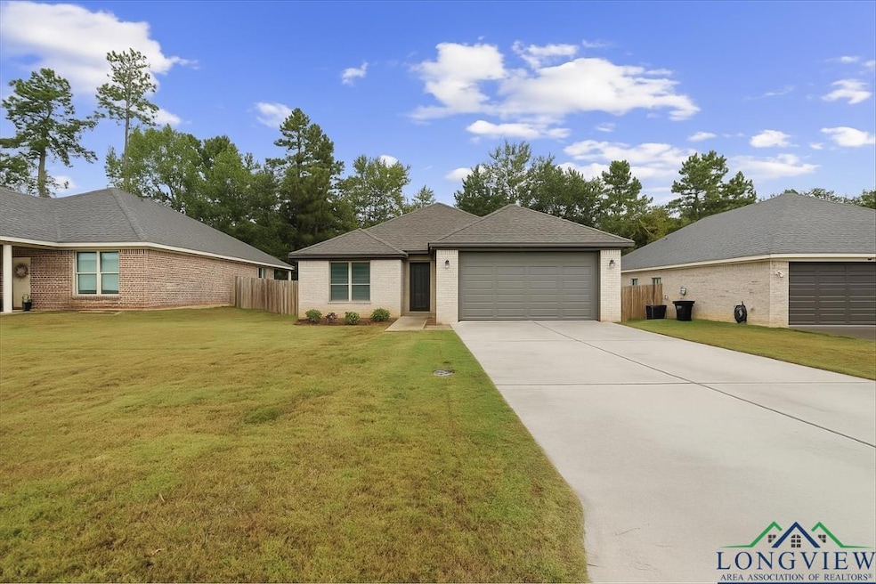 Ranch-style home featuring driveway, brick siding, roof with shingles, and an attached garage