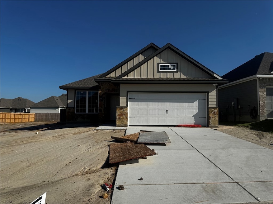 View of front of property with stone siding, board and batten siding, concrete driveway, and a garage