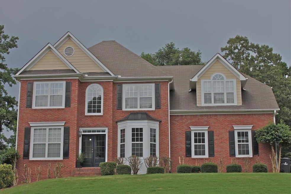 View of front of property featuring a front lawn, brick siding, and french doors
