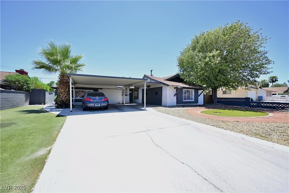 View of front facade featuring an attached carport, concrete driveway, and a putting area