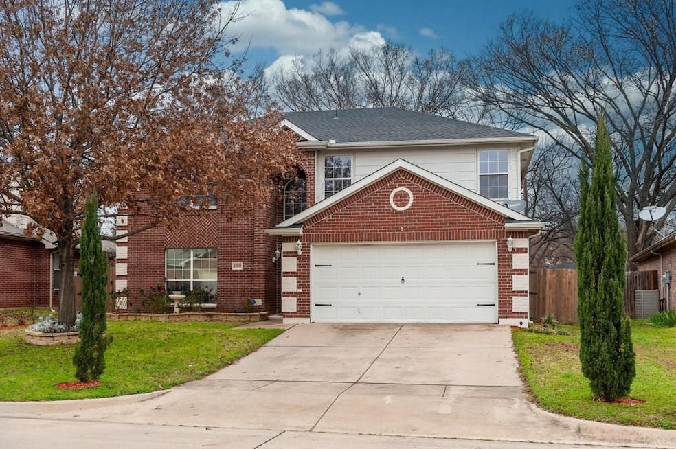 Traditional-style house featuring a front lawn, concrete driveway, brick siding, and a garage