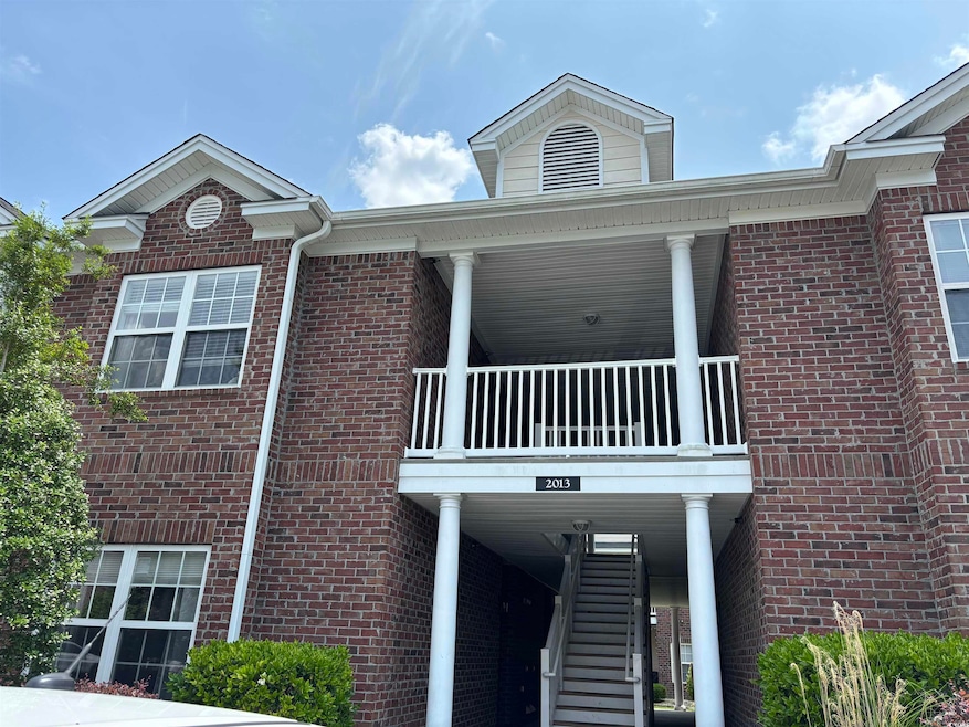View of front of home featuring brick siding, a balcony, and stairs