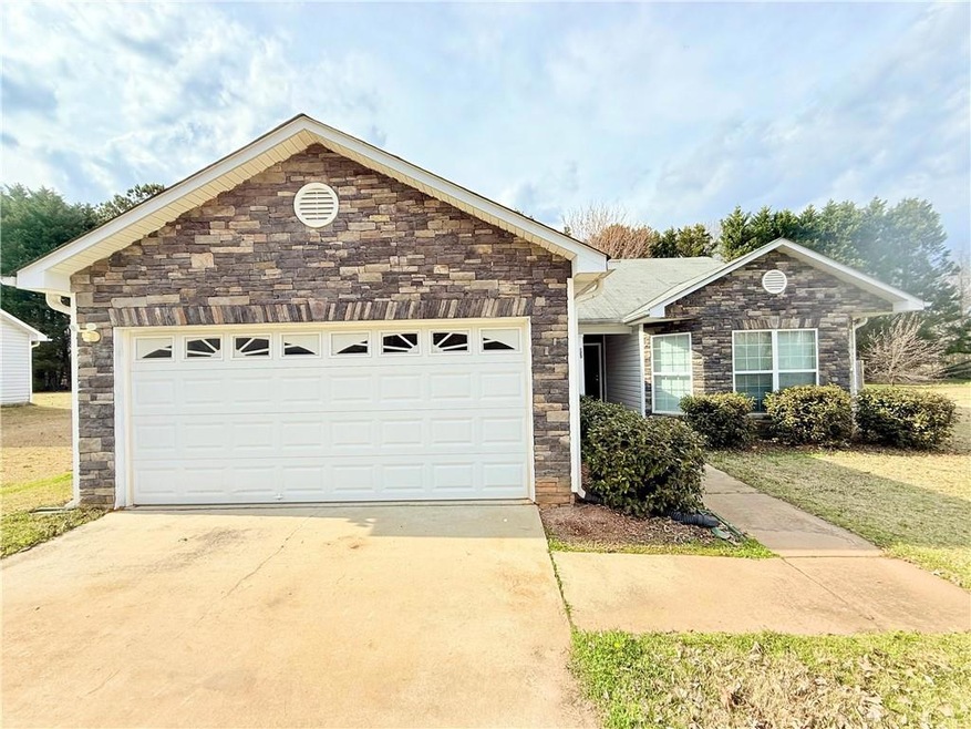 Ranch-style house with a garage, stone siding, and