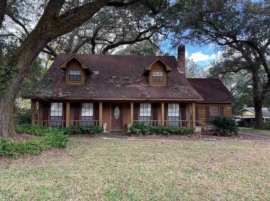 View of front facade featuring a porch, a chimney, and a front lawn