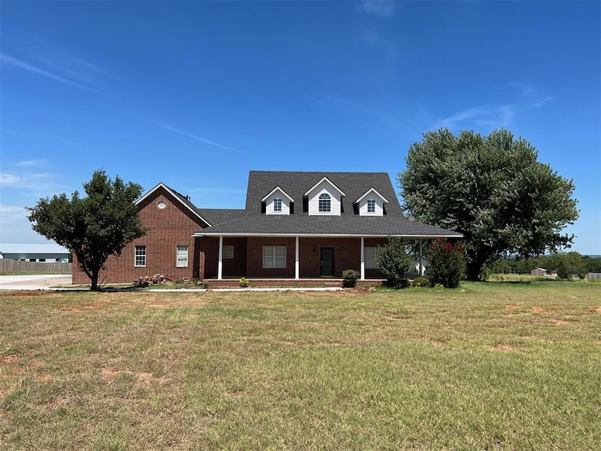 View of front of house featuring covered porch, a front lawn, and brick siding