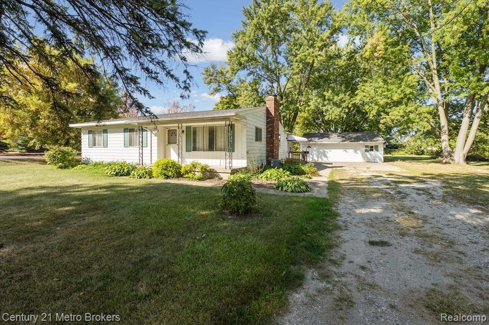 View of front of property with a front yard, a chimney, and an outdoor structure
