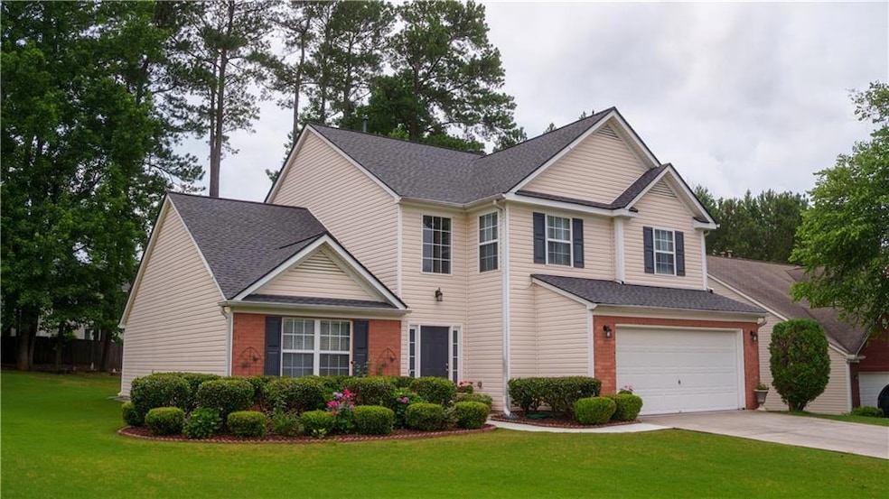Traditional-style house featuring driveway, a front lawn, brick siding, and a garage