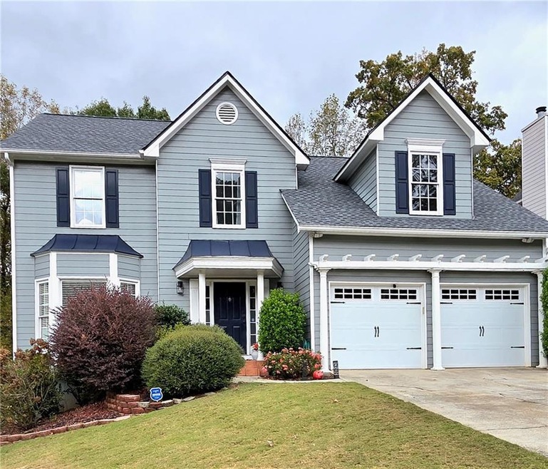 View of front of property with a shingled roof, concrete driveway, and a front yard