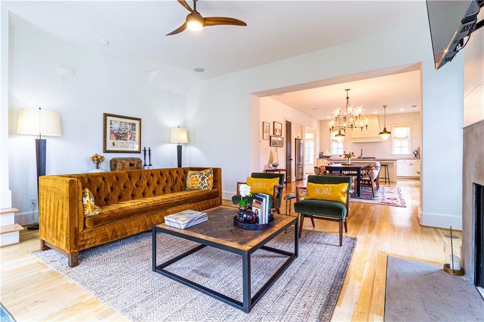 Living room with ceiling fan with notable chandelier and light hardwood / wood-style floors