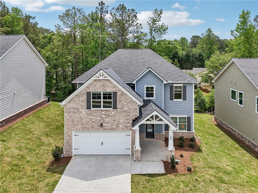 View of front facade with brick siding, an attached garage, concrete driveway, and a front lawn