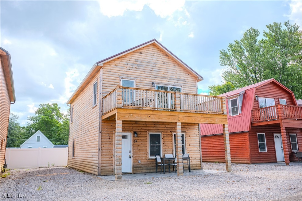 Rear view of house with faux log siding, a gambrel roof, and a patio