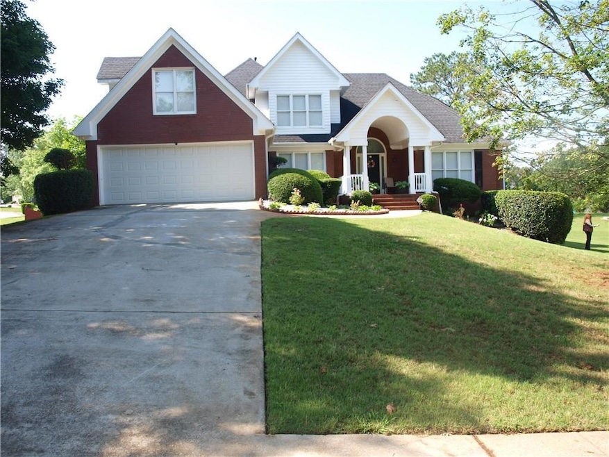Traditional-style house featuring driveway, a front lawn, an attached garage, and covered porch