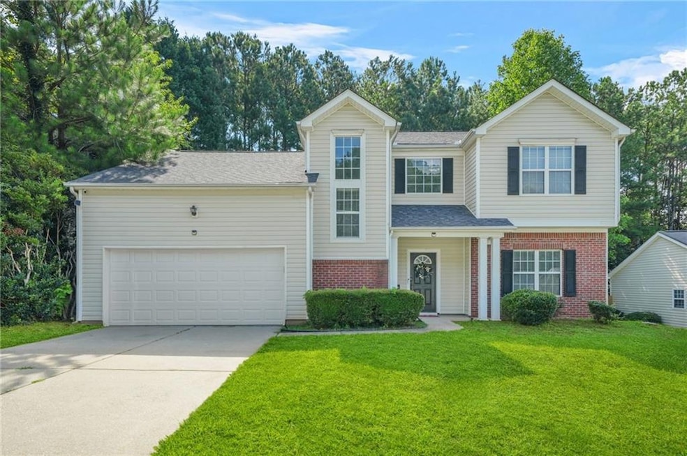 Traditional home featuring brick siding, driveway, a garage, a front lawn, and a shingled roof