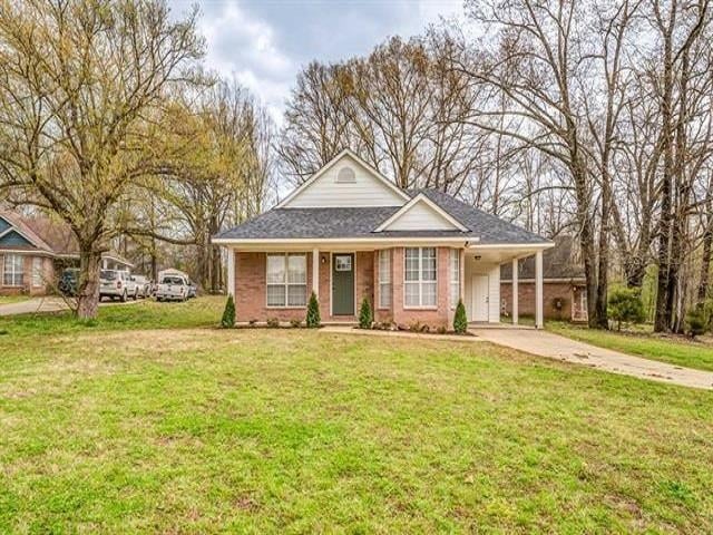 View of front of home with concrete driveway, a front lawn, a carport, and brick siding