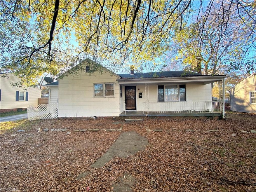 Front of home with an abundance of trees and large covered front porch