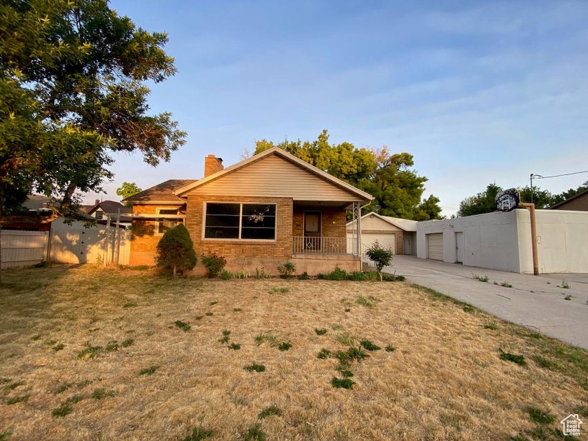 View of front of house with a chimney, an outbuilding, covered porch, and a detached garage