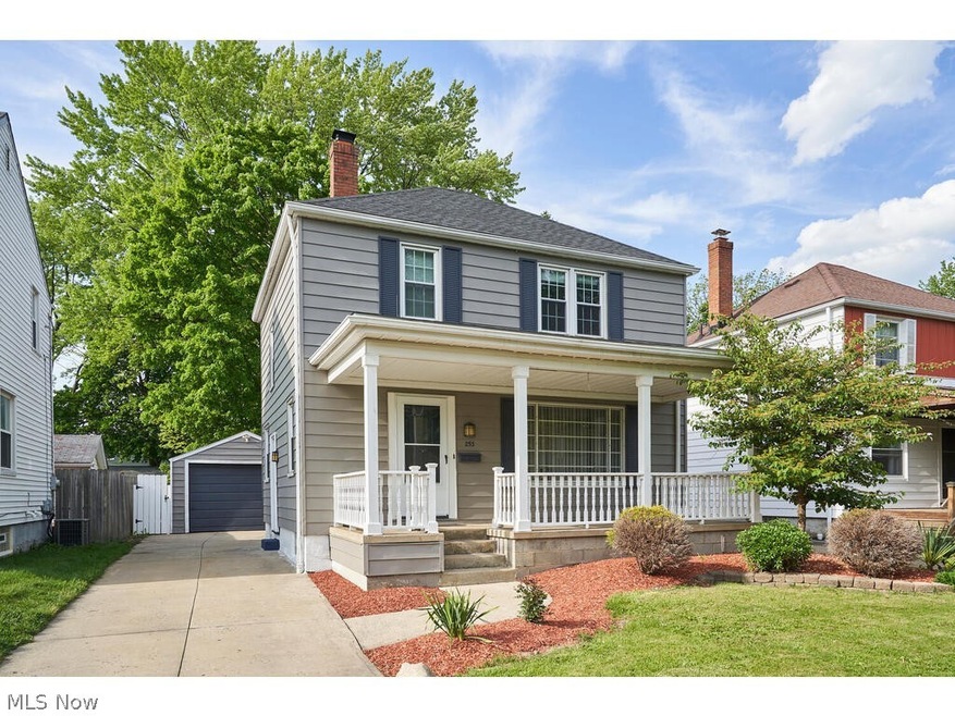 View of front of home featuring a garage, an outdoor structure, and a porch