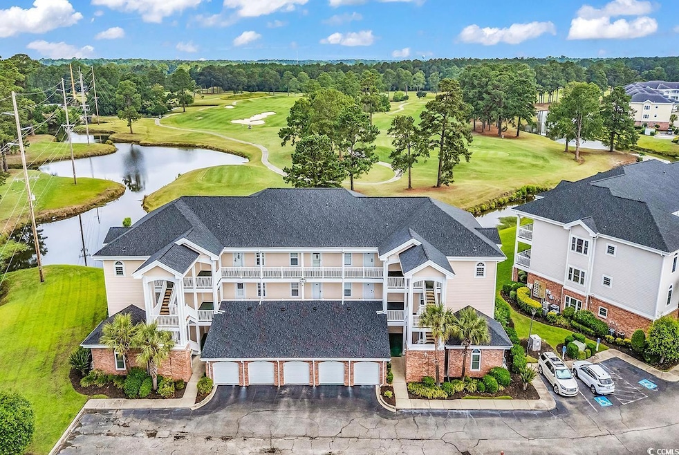 Drone / aerial view of a golf club, a nearby body of water, and a tree filled landscape