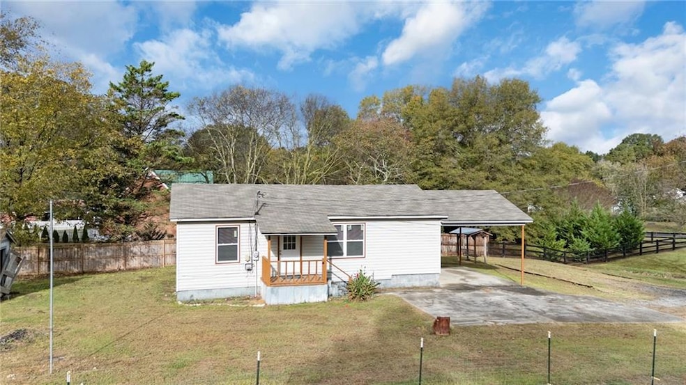 View of front facade featuring driveway, an attached carport, a shingled roof, a patio, and crawl space