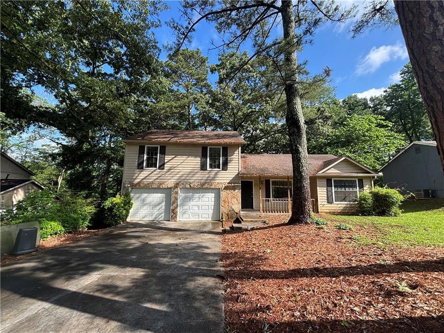 Front of home featuring a porch, driveway, a garage, and stone siding