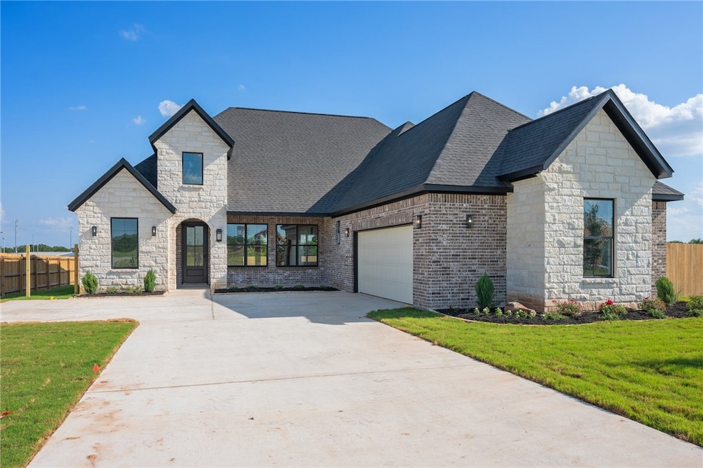 French country home with a garage, concrete drivew