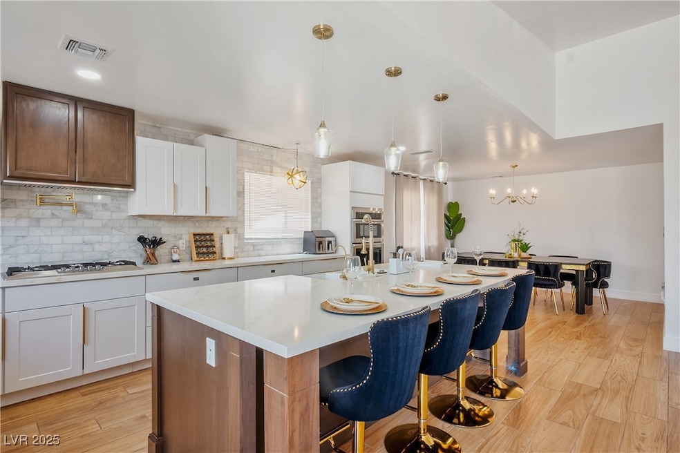 Kitchen featuring white cabinetry, decorative light fixtures, brown cabinets, and a breakfast bar area