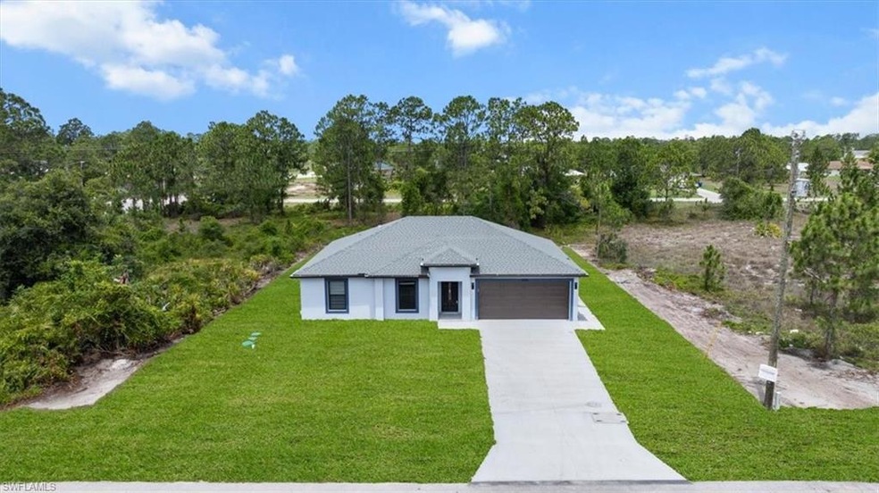 View of front of house with a front yard, concrete driveway, a garage, and stucco siding