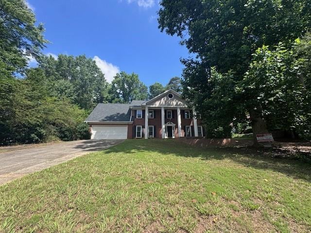Neoclassical home featuring an attached garage, driveway, and a front lawn