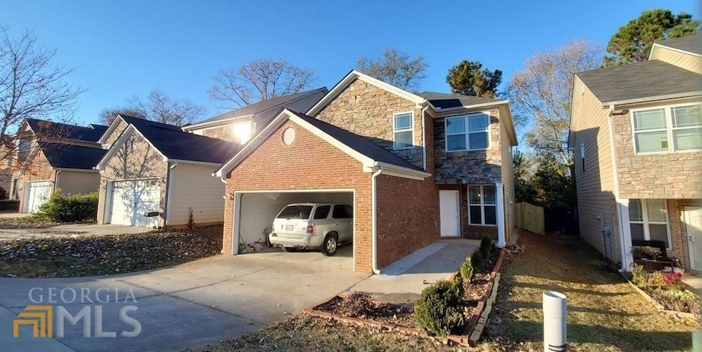View of side of home with an attached garage, concrete driveway, brick siding, and stone siding