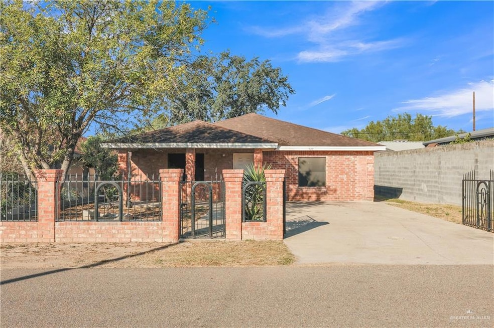 View of front of property with a fenced front yard, a gate, brick siding, and roof with shingles