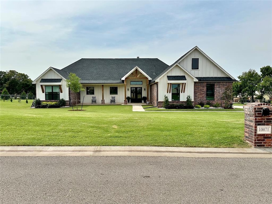 Modern farmhouse with board and batten siding, a porch, a shingled roof, a front lawn, and brick siding