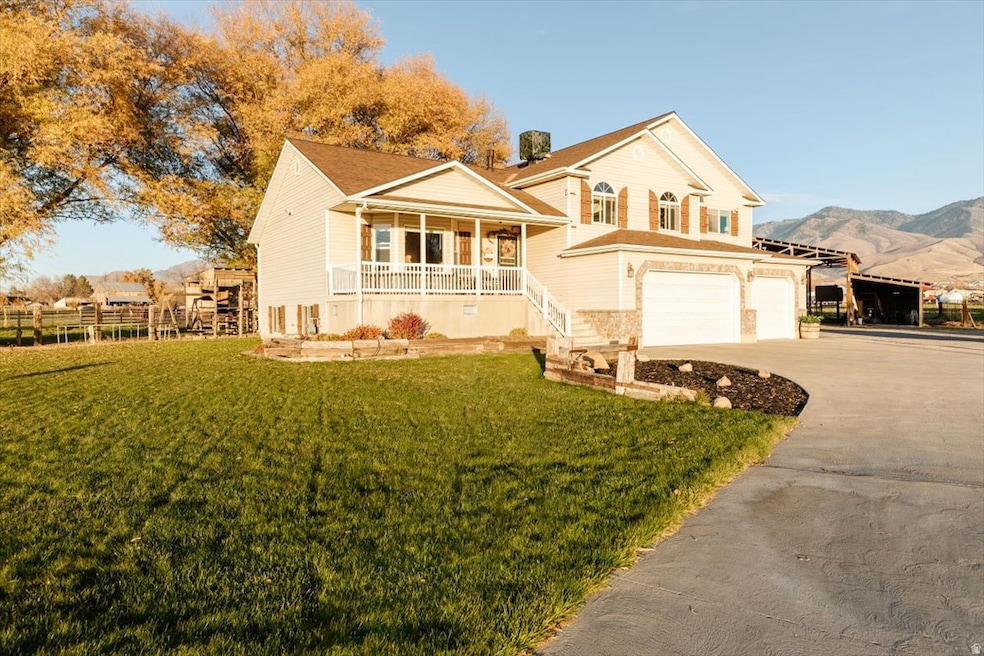 View of front of property featuring covered porch, a front yard, driveway, an attached garage, and a mountain view