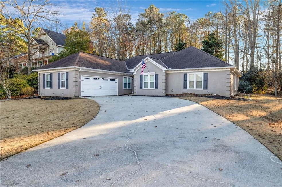 Single story home featuring concrete driveway, stucco siding, roof with shingles, and an attached garage