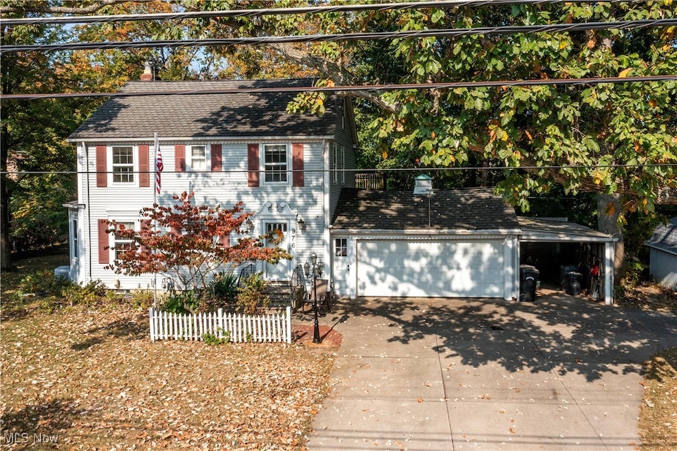 Colonial inspired home with driveway and view of scattered trees