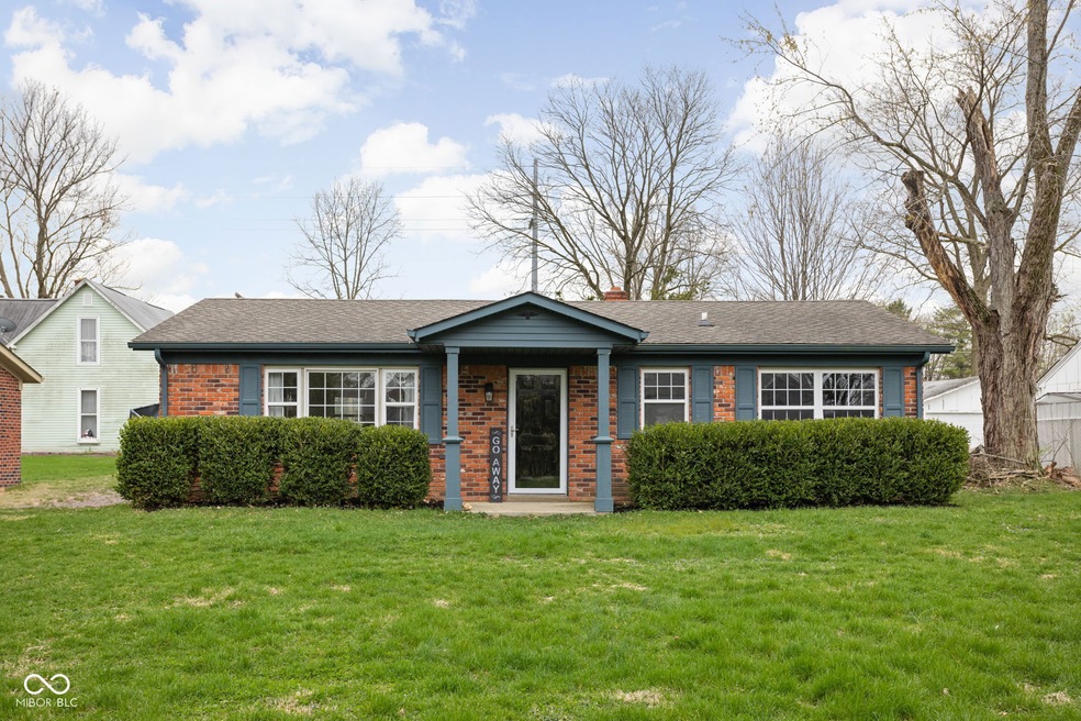 view of front of home with brick siding, a front lawn, and a shingled roof