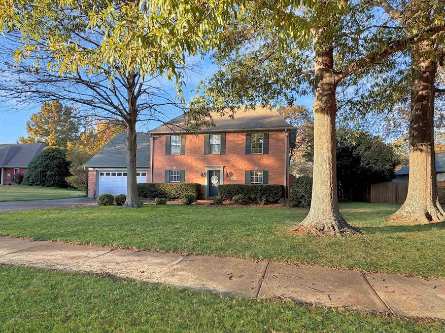 Colonial home featuring a front lawn, brick siding, and a garage