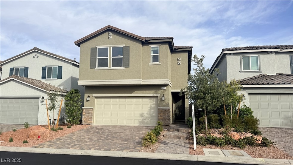 Traditional home featuring stucco siding, stone siding, decorative driveway, and an attached garage
