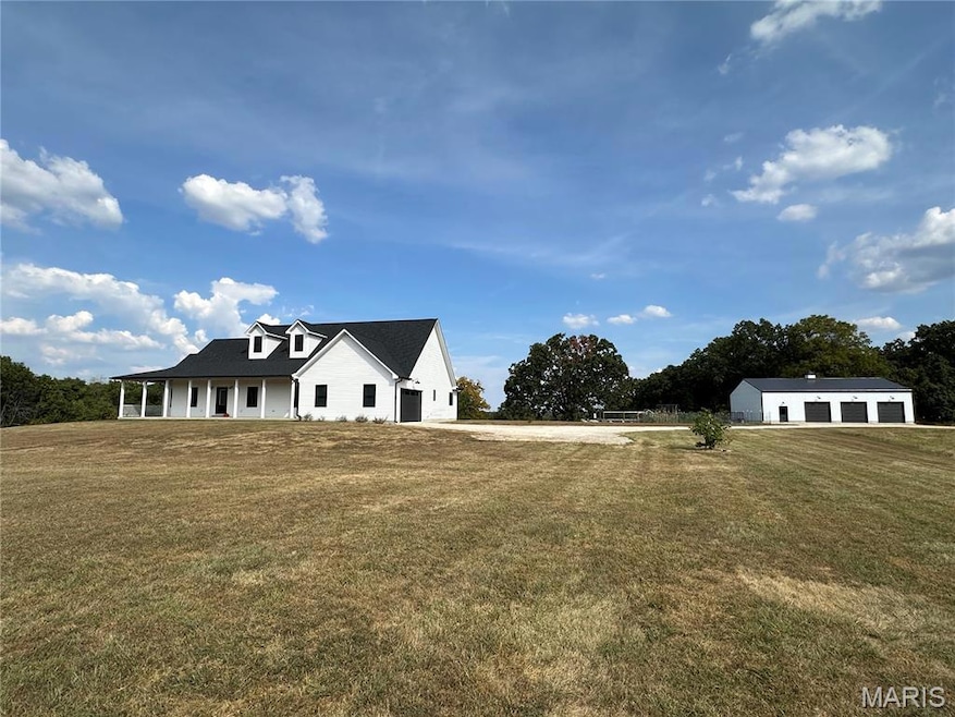 Modern inspired farmhouse with a front yard, covered porch, a detached garage, and an outdoor structure