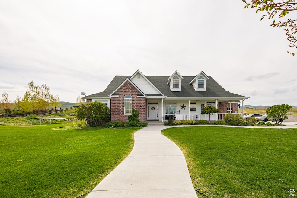 View of front of home with covered porch, a front yard, and brick siding