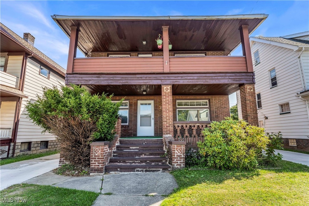 View of front of property with a porch, brick siding, a balcony, and a front lawn