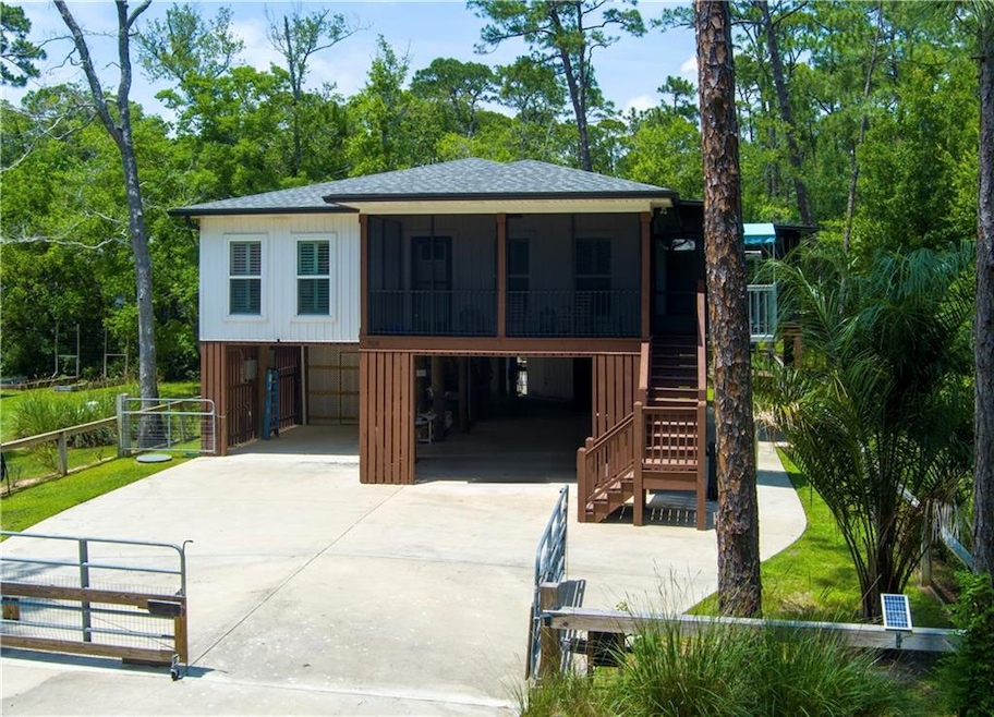 Coastal home with a sunroom, driveway, a carport, a shingled roof, and stairway