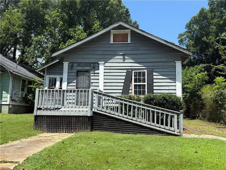 View of front facade with a wooden deck and a front yard
