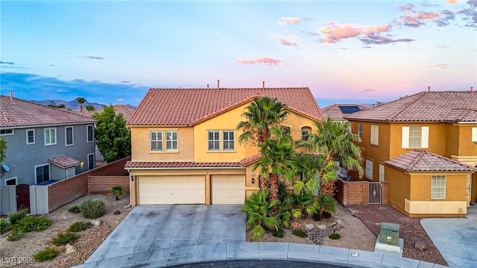 Mediterranean / spanish-style house with a gate, an attached garage, stucco siding, driveway, and a tiled roof