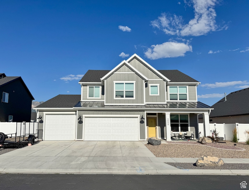 View of front of property featuring a porch, a standing seam roof, driveway, and a metal roof