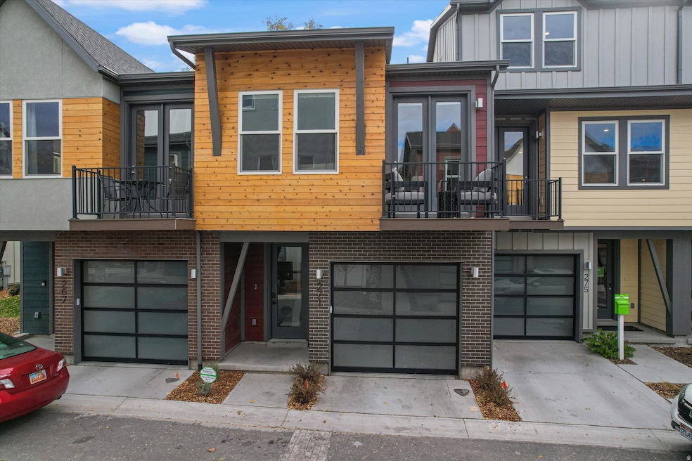 Contemporary home with a balcony, driveway, a garage, and brick siding