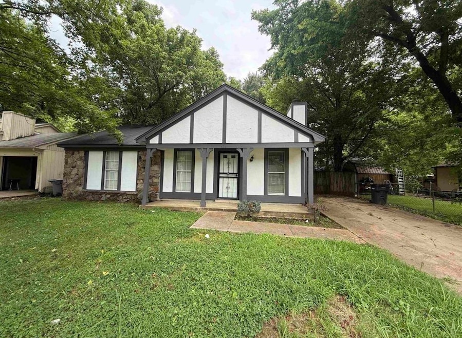 View of front of property featuring a chimney, a porch, stone siding, driveway, and stucco siding