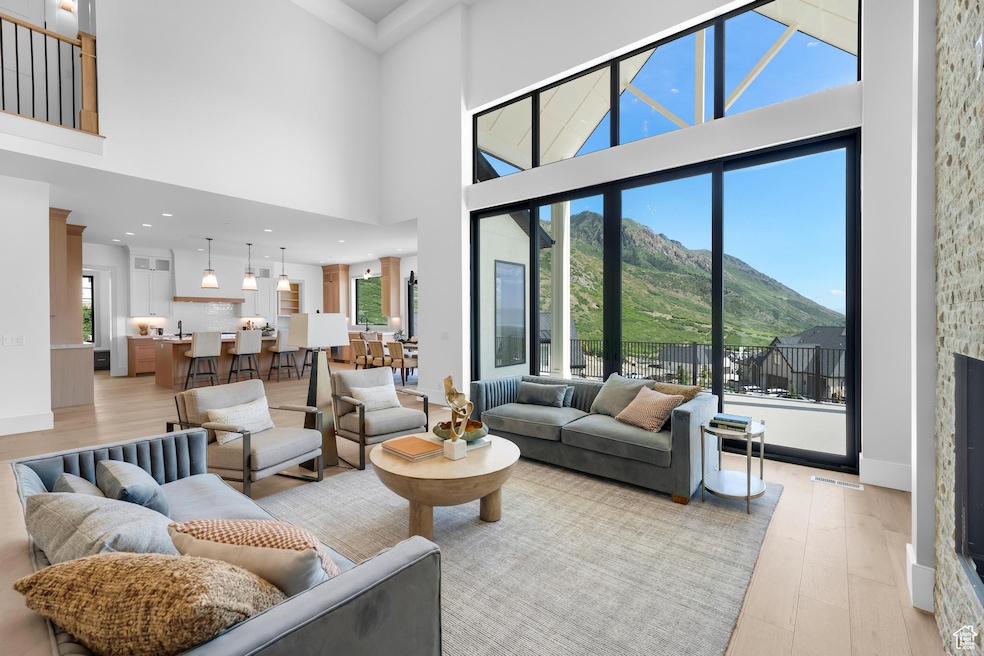 Living area with a mountain view, light wood-style flooring, healthy amount of natural light, a towering ceiling, and baseboards