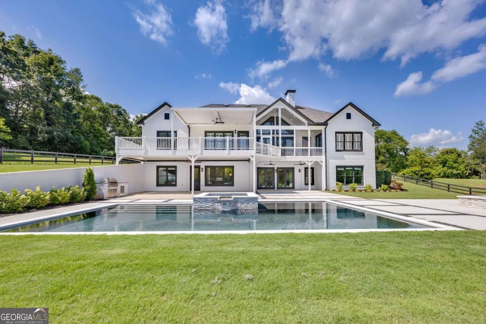 Back of property featuring a balcony, a patio area, a pool with connected hot tub, stucco siding, and a chimney